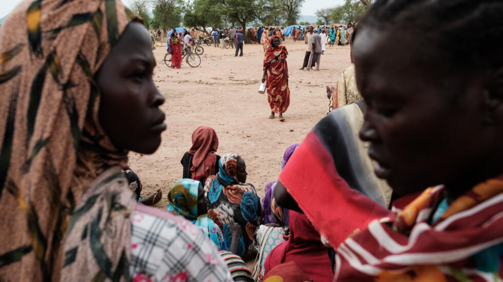 Un grupo de personas recién llegadas a un campo de desplazados internos aguarda a recibir tarjetas para el reparto de alimentos, el 17 de junio de 2024 en Agari (Sudán)