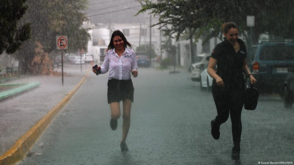 Personas corren bajo fuerte lluvia causada por el huracán 'Alberto', en México.