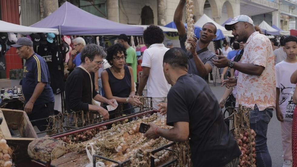 Los compradores se reúnen alrededor de un carro de ajos en un mercado callejero en La Habana, Cuba, el sábado 16 de marzo de 2024.
