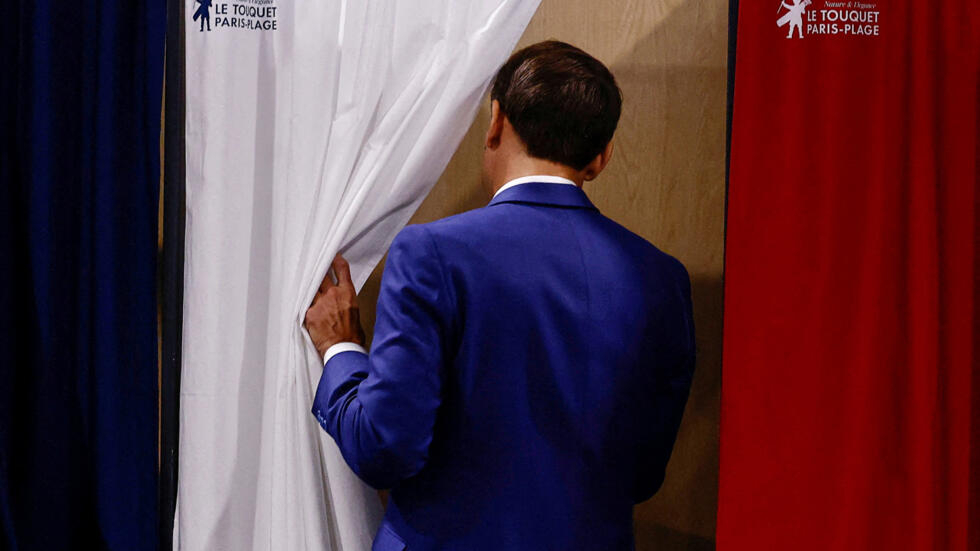 El presidente francés, Emmanuel Macron, entra en una cabina electoral para votar en la primera vuelta de las elecciones legislativas anticipadas, en Le Touquet-Paris-Plage, el 30 de junio de 2024.