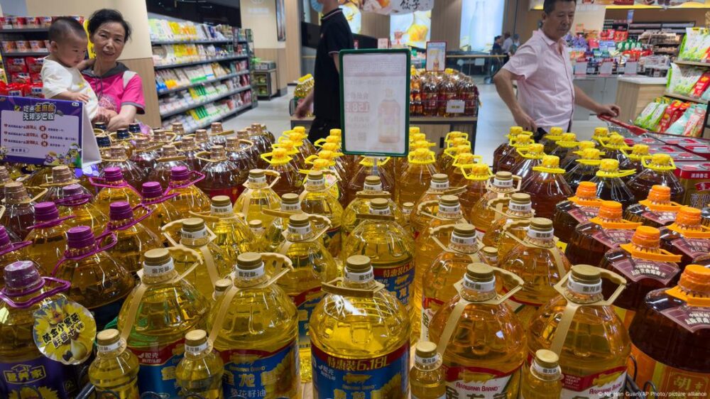 China: aceites de cocina, en un supermercado, observados por varios consumidores, incluida una mujer con un bebé en brazos.