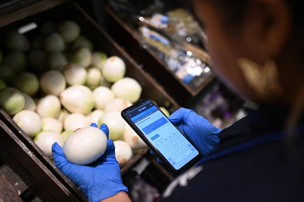 Un inspector de la Defensoría del Consumidor verifica los precios y el tamaño de cebollas en su supermercado de San Salvador, el 8 de julio de 2024