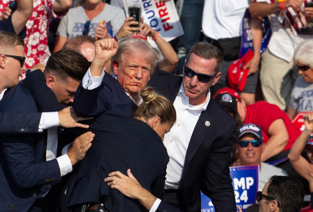 El expresidente estadounidense Donald Trump, herido en una oreja, levanta el puño tras sufrir un atentado en Butler, Pensilvania, el 13 de julio de 2024