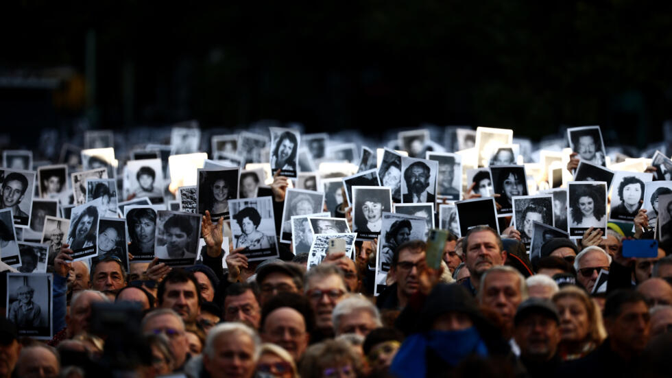 Personas sostienen fotos de víctimas durante ceremonia por los 30 años del atentado contra el centro judío AMIA en Buenos Aires, el 18 de julio de 2024