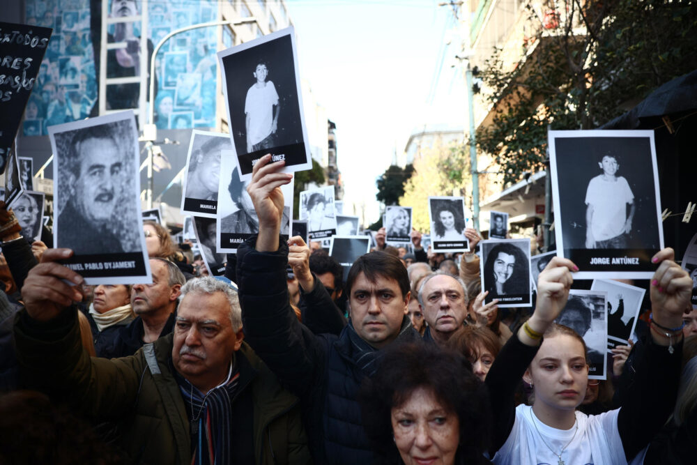 Personas sostienen fotos de las víctimas durante la ceremonia por el 30 aniversario del atentado contra el centro judío AMIA en Buenos Aires, el 18 de julio de 2024