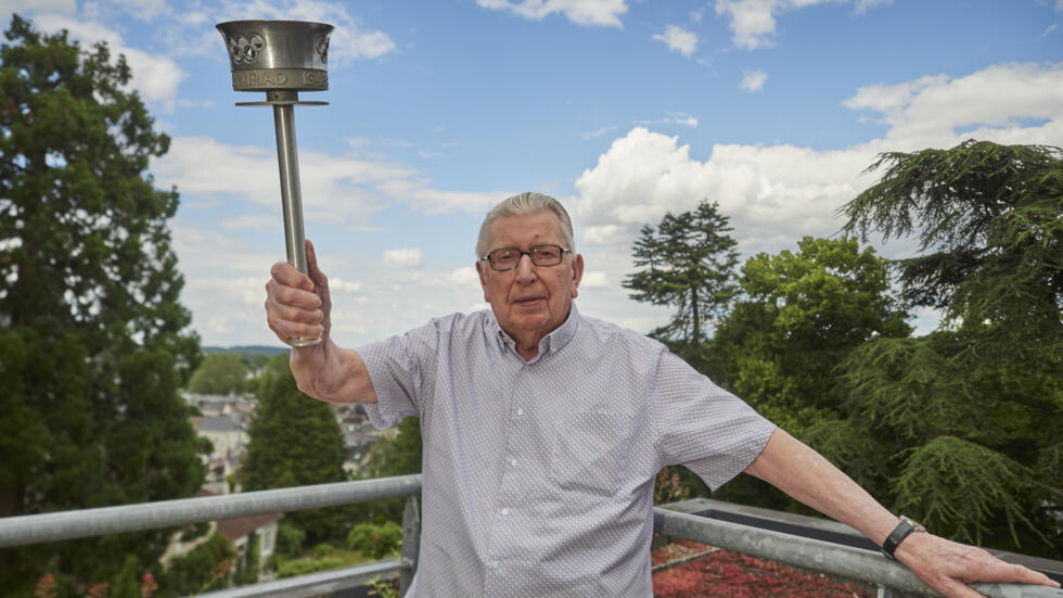 El excorredor de 99 años, Daniel Rebiffe, posa con una copia de la antorcha olímpica de Londres 1948 en Amboise, en el centro de Francia el 11 de junio de 2024.