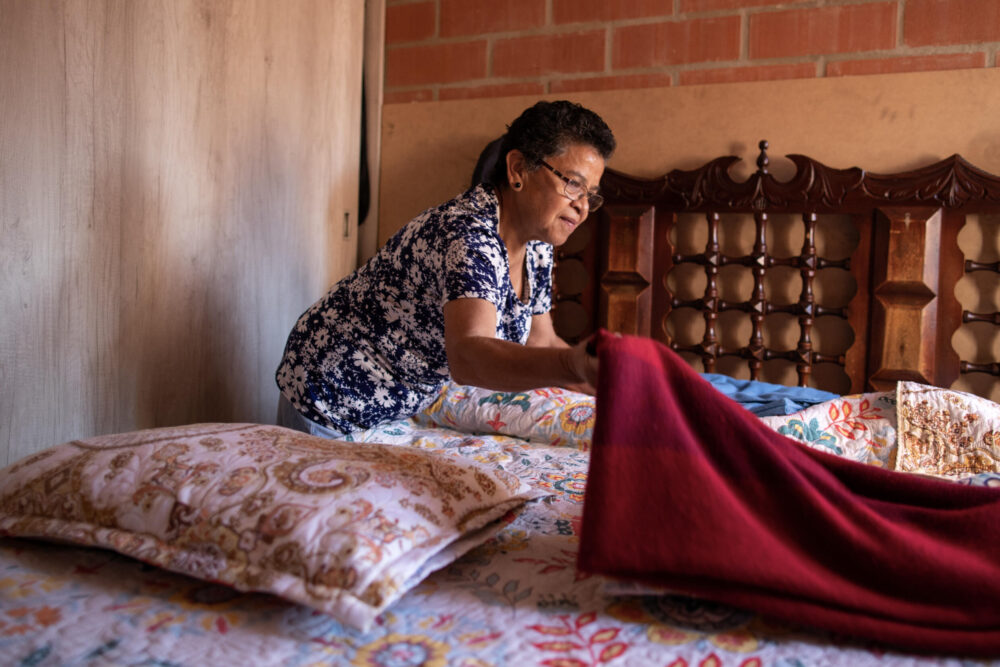 La colombiana Deyanira Cruz, de 65 años, hace la cama en su apartamento, el 17 de julio de 2024 en Soacha, carca de Bogotá