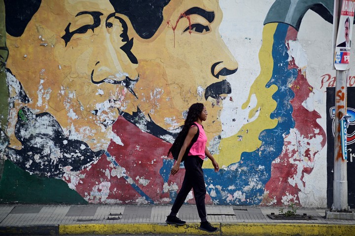Una mujer camina junto a un mural que representa al fallecido expresidente venezolano Hugo Chávez y al presidente venezolano Nicolás Maduro en Caracas. Foto Reuters