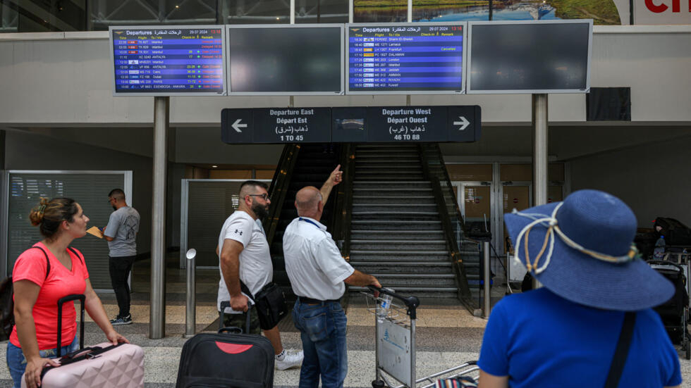 Pasajeros consultan los horarios de vuelo en el aeropuerto internacional Rafic Hariri tras el retraso o la cancelación de sus vuelos en Beirut el 29 de julio de 2024.