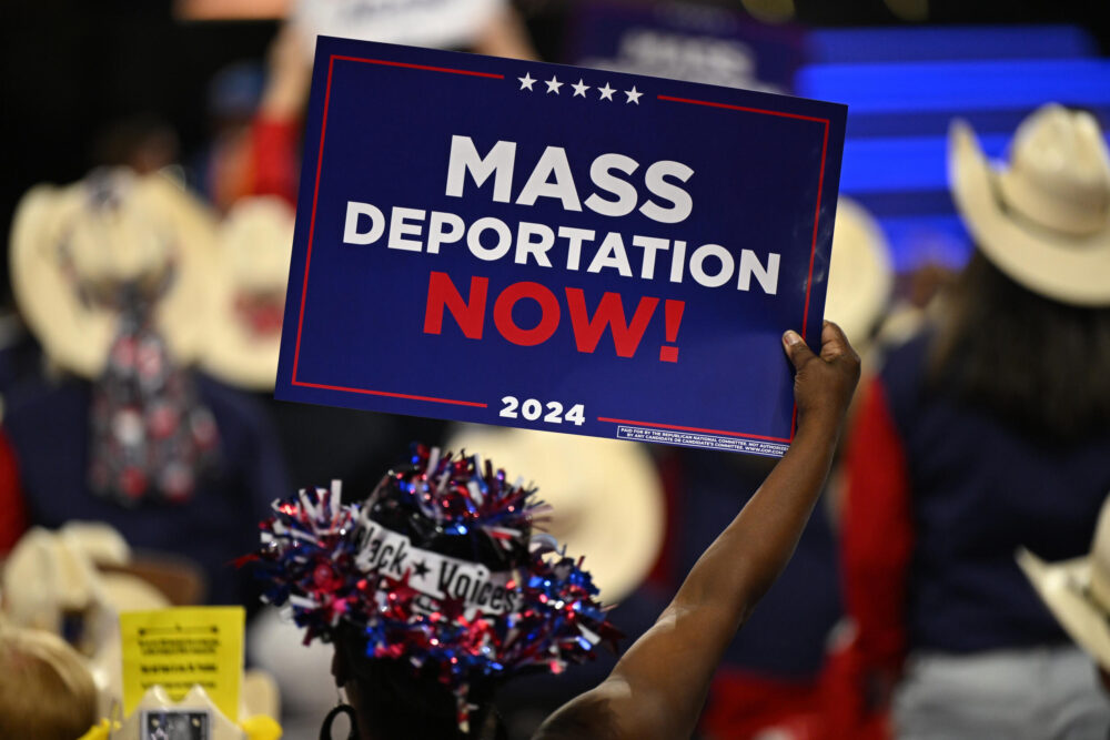 Una persona sostiene un cartel que dice "¡Deportaciones masivas ahora!" durante el tercer día de la Convención Nacional Republicana de 2024 en el Foro Fiserv en Milwaukee, Wisconsin, el 17 de julio de 2024