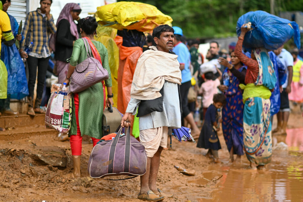 Trabajadores de plantaciones de té afectados por los deslizamientos de tierras se dirigen a un campamento de acogida cargados con algunas pertenencias, el 31 de julio de 2024 en el distrito de Wayanad, al sur de India