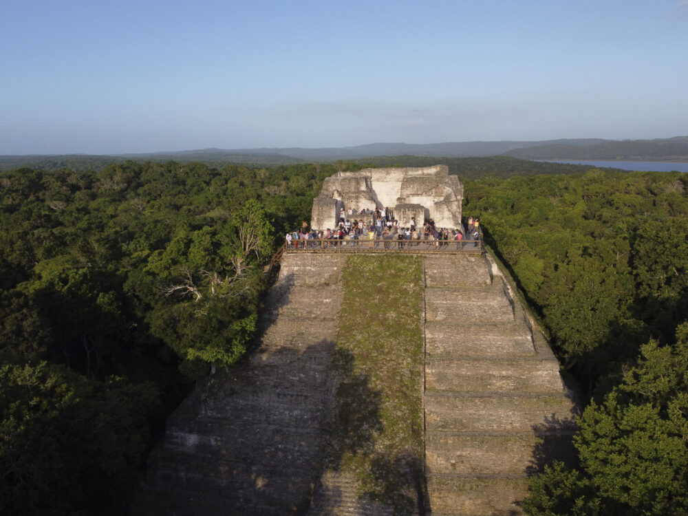 Vista aérea de líderes amazónicos colombianos y turistas caminando en el sitio arqueológico de Yaxha, en la Biosfera Maya de Petén, Guatemala, el 24 de julio de 2024