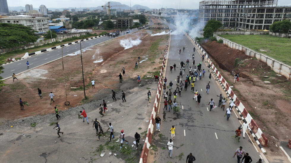 Unos manifestantes huyen de los gases lacrimógenos lanzados por las fuerzas de seguridad de Nigeria durante una protesta el 2 de agosto de 2024 en Abuja