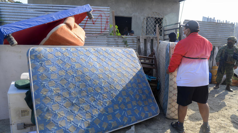 Un hombre saca muebles y pertenencias de gente que extorsionó y echó a su familia, tras recuperar su casa durante un operativo llevado a cabo por la policía en Durán, 10 km al este de Guayaquil, en Ecuador, el 23 de julio de 2024