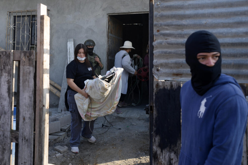 Miembros de una familia sacan muebles y pertenencias de gente que las extorsionó y echó de su casa, tras recuperarla durante un operativo llevado a cabo por la policía en Durán, 10 km al este de Guayaquil, en Ecuador, el 23 de julio de 2024