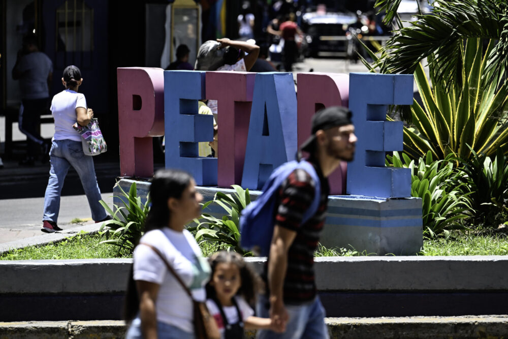 Des passants devant "Petare" en lettres de ciment, le nom d'un immense bidonville dans l'est de Caracas, le 1er août 2024.
