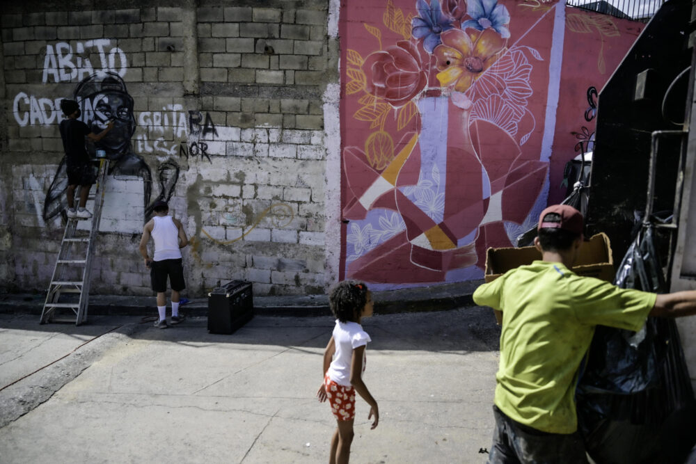 Deux jeunes écrivent "Brisons nos chaînes" sur un mur du bidonville de Petare, dans l'est de Caracas, dont proviennent nombre de manifestants opposés à la réélection du président Nicolas Maduro pour un troisième mandat, le 1er août 2024.
