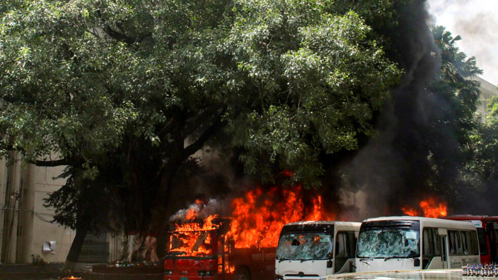 Unos autobuses arden en la Facultad de Medicina Bangabandhu Sheikh Mujib de Daca el 4 de agosto de 2024, tras unos enfrentamientos entre estudiantes y partidarios del gobierno bangladesí durante una protesta