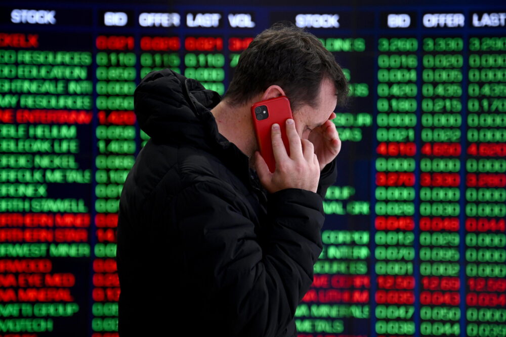 Un inversor habla delante las pantallas que reflejan las caídas en las bolsas de Australia y Nueva Zelanda este lunes, 5 de agosto.