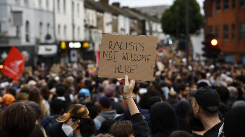 Una manifestante muestra una pancarta con el lema "Los racistas no son bienvenidos aquí" durante una protesta en el barrio londinense de Walthamstow, el 7 de agosto de 2024