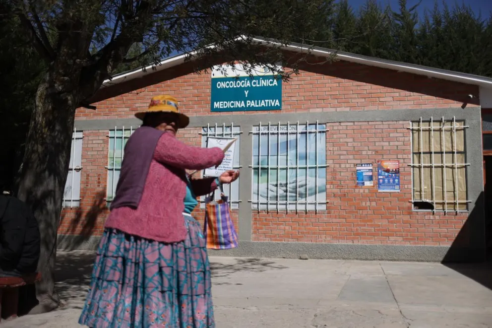 Una mujer caminando frente a la fachada de la clínica de radioterapia del Seguro Universal de Bolivia, en La Paz (Bolivia). Foto: EFE / Luis Gandarillas