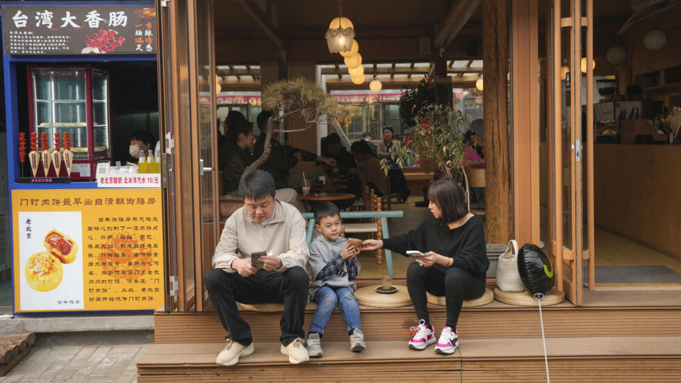 Una familia sentada frente a una cafetería cerca del templo Yonghegong Lama en Pekín, el miércoles 3 de abril de 2024. (Imagen de ilustración)