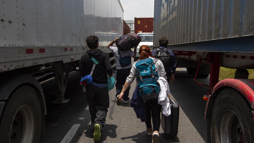 Una familia camina con sus maletas a cuestas intentando llegar a tiempo al aeropuerto de Bogotá, Colombia, en medio a un bloqueo de transportistas que causó caos en el tránsito, el 3 de septiembre de 2024.