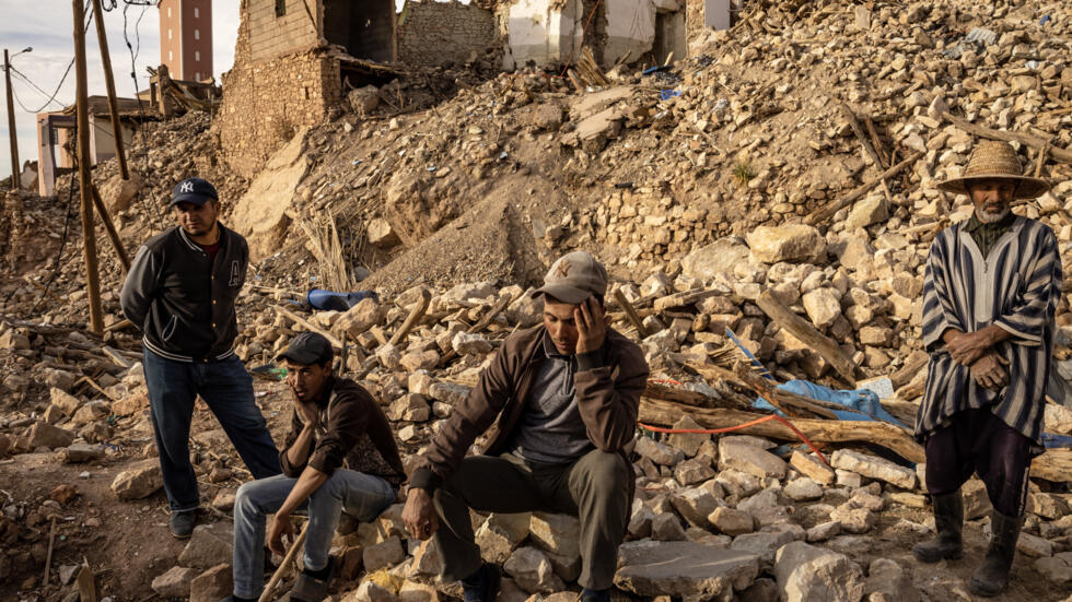 Personas sentadas en medio de los escombros en el pueblo de Duzru, en el centro de Marruecos, el 13 de febrero de 2024