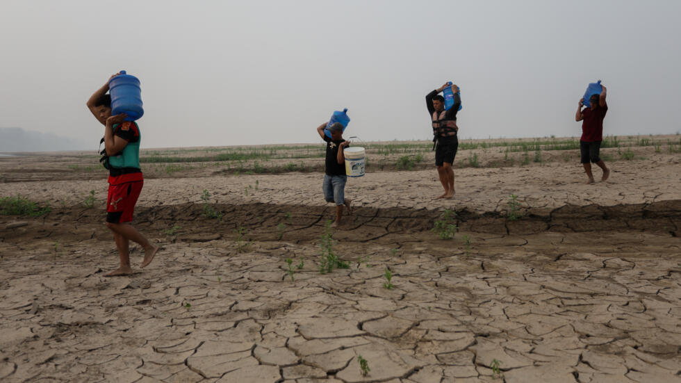 Un grupo de personas camina con bidones de agua sobre las márgenes secas del río Madeira en Humaita, Brasil, el 7 de spetiembre de 2024.