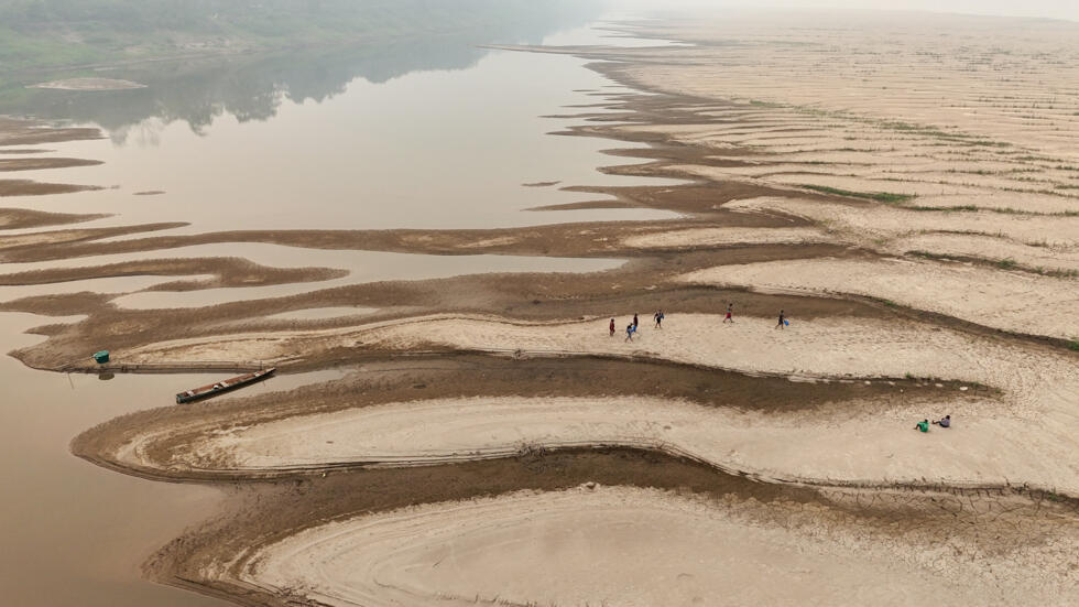 Personas caminan junto al río Madeira en la comunidad Paraizinho , en Humaita, estado de Amazonas, Brasil. El gobierno evalúa reimplantar el horario de verano para ahorrar energía por la sequía