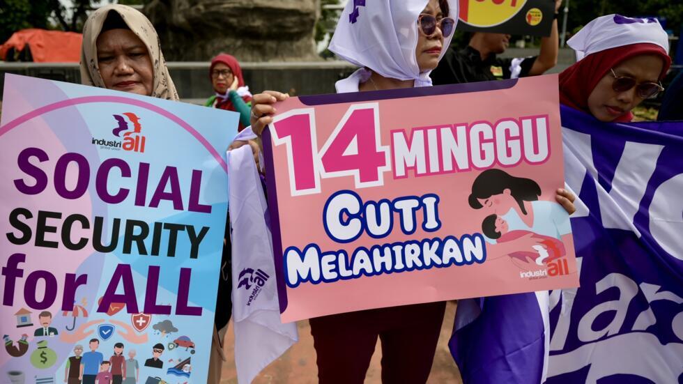 Una mujer indonesia sostiene un cartel con la frase 'Seguridad social para todos' durante una manifestación con motivo del Día Internacional de la Mujer para pedir al gobierno aprobar medidas contra la discriminación, el 8 de marzo de 2024 en Yakarta