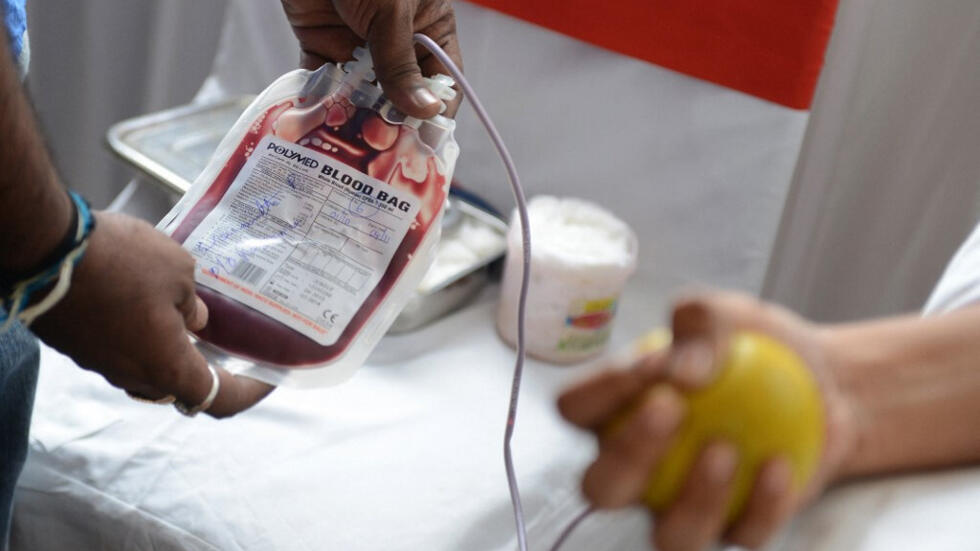 Un voluntario médico indio (izquierda) comprueba una bolsa de sangre tras una concentración para celebrar el Día Nacional del Donante Voluntario de Sangre en Hyderabad el 1 de octubre de 2013. (Imagen ilustrativa).