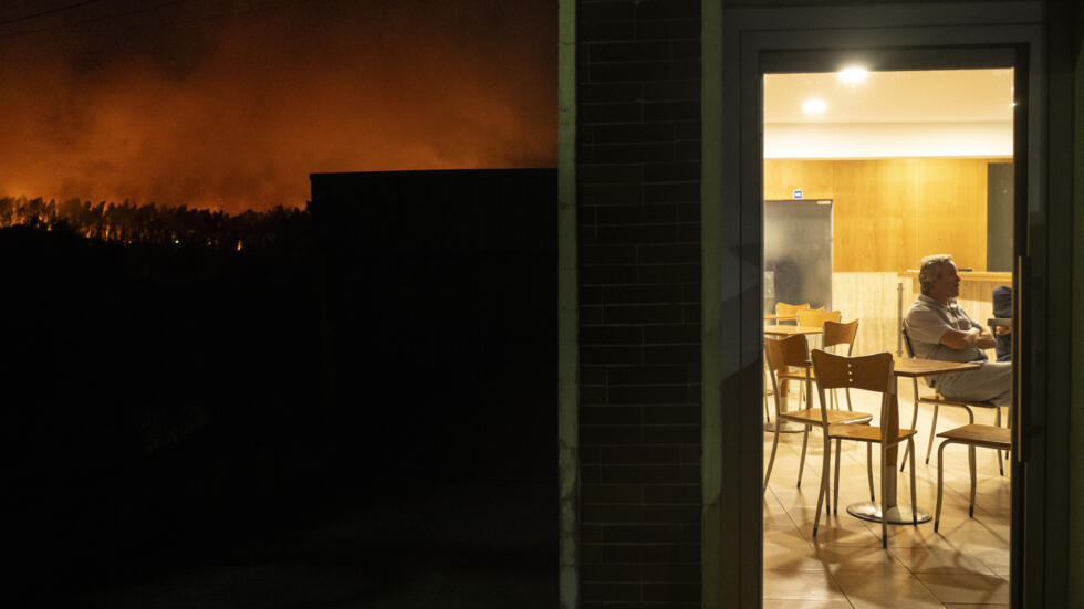 Un hombre, sentado en una cafetería durante un incendio en la localidad de Veiga, en la región portuguesa de Aveiro, el 17 de septiembre de 2024