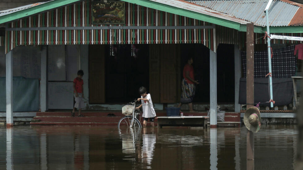 Un niño empuja una bicicleta entre las aguas en la inundada aldea de Demoso, en el estado birmano de Kayah, el 18 de septiembre de 2024