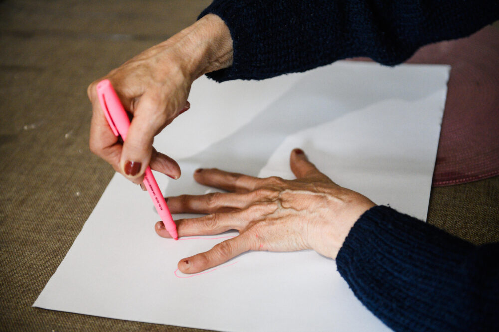 Una paciente con alzheimer dibuja el contorno de su mano durante una actividad organizada en una residencia el 9 de mayo de 2023 en Arles, en el sureste de Francia