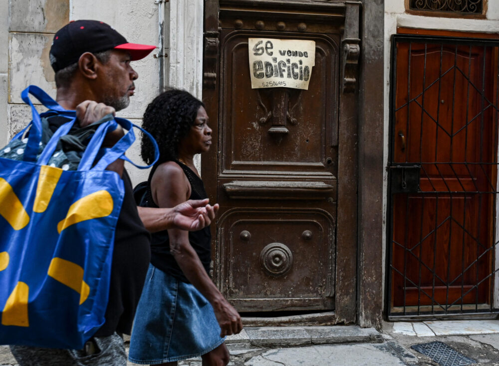 Dos personas pasan frente a un edificio en venta en La Habana el 1 de Octubre de 2024.