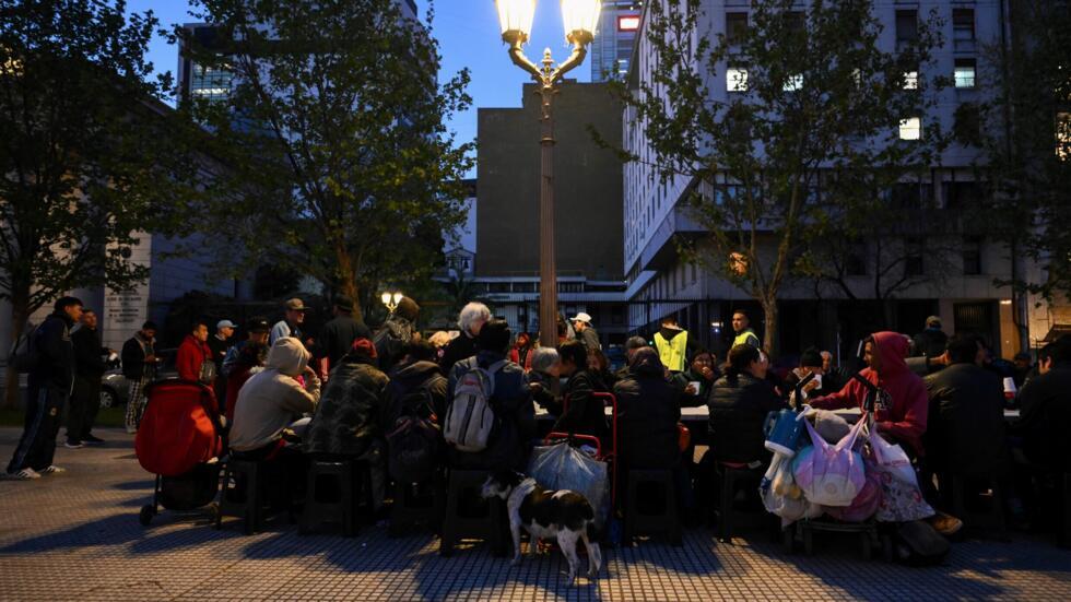 Unas personas comen alimentos distribuidos por la organización Red Solidaria el 25 de septiembre de 2024 en la Plaza de Mayo de Buenos Aires