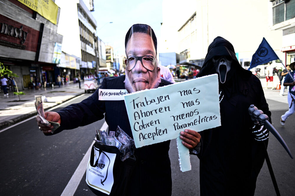 Un trabajador con una máscara con la imagen del nuevo director de la Caja del Seguro Social, Dino Mon Vásquez, y otro simbolizando la muerte, en las protestas contra la reforma de las pensiones, en Ciudad de Panamá, el 17 de octubre de 2024