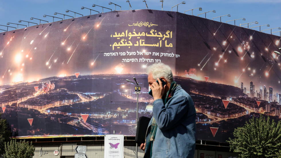 Un hombre pasa frente a un gran cartel anti-israelí que cubre la fachada de un edificio, el 26 de octubre de 2024 en Teherán