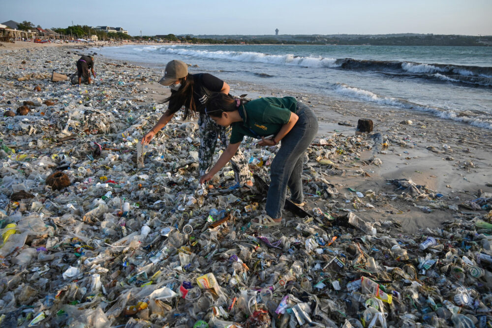 Dos personas inspeccionan plásticos y otros desechos acumulados en la playa de Kedonganan, en la isla indonesia de Bali, el 19 de marzo de 2024