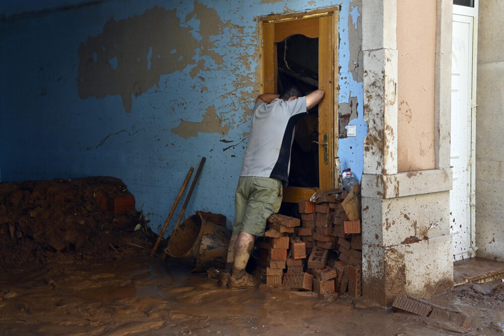 Un hombre se apoya en una puerta rota para recuperar fuerzas durante las tareas de limpieza de una casa devastada por las inundaciones, el 1 de noviembre de 2024 en la localidad española de Paiporta, cerca de Valencia