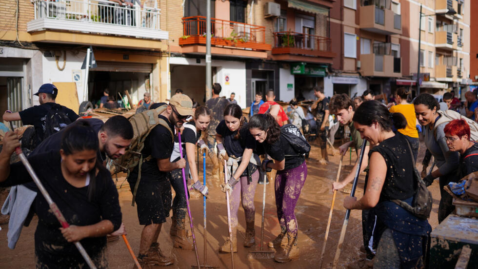 Voluntarios y vecinos limpian el barro de las calles de la localidad de Paiporta el 1 de noviembre de 2024, tras las devastadoras inundaciones que azotaron la región de Valencia, en el este de España