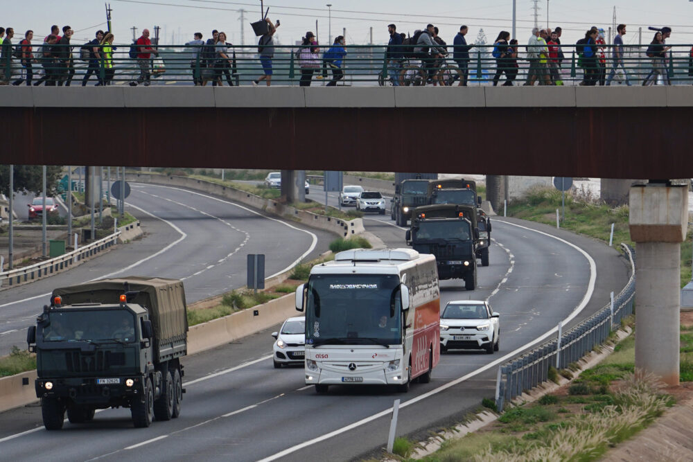 Vehículos militares pasan por debajo de un puente cruzado por voluntarios que se dirigen al barrio de La Torre para ayudar en las labores de limpieza, el el 1 de noviembre de 2024, tras unas devastadoras inundaciones, en Valencia, este de España