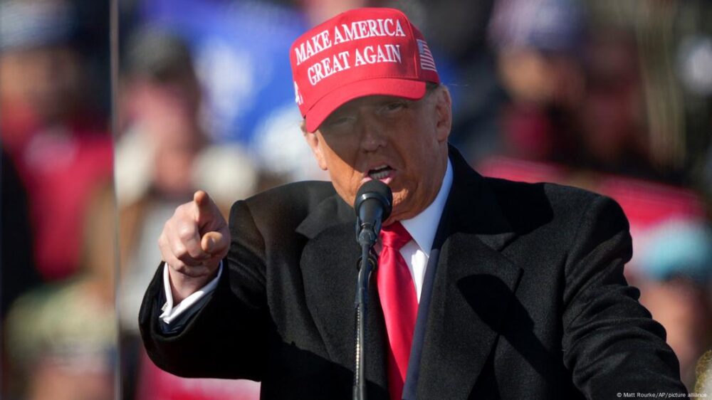 El candidato republicano señala con el dedo mientras habla al micrófono portando una gorra con su eslogan "make America great again".