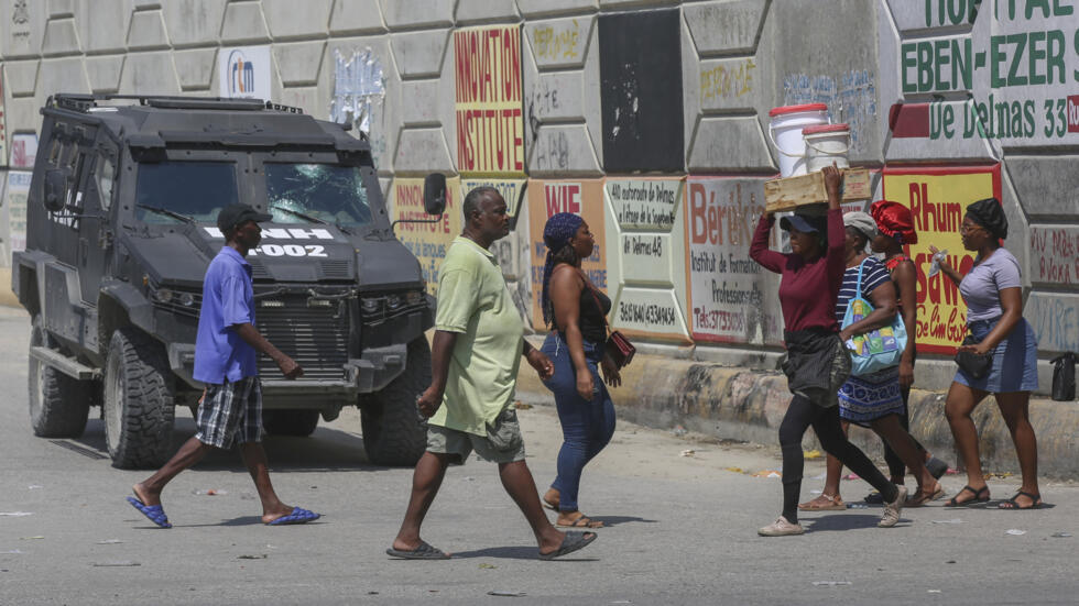 Peatones pasan junto a un vehículo policial blindado en Puerto Príncipe, Haití, el viernes 4 de octubre de 2024.