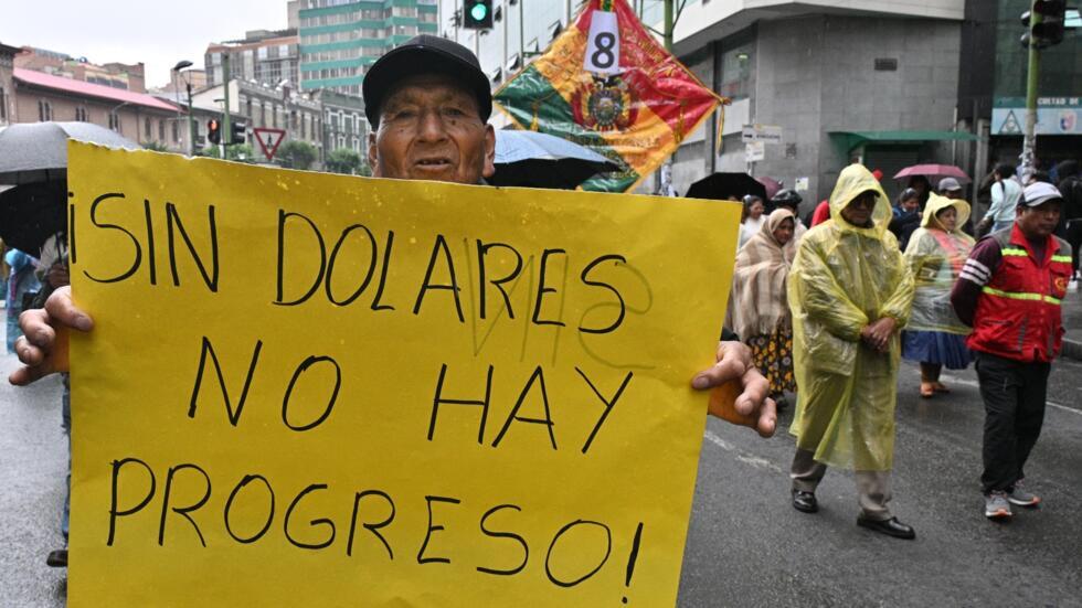 Un hombre lleva un cartel que dice "sin dólares no hay progreso" durante una protesta contra la escasez de combustible y dólares en La Paz, el 21 de noviembre de 2024.