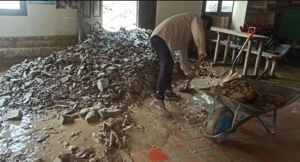 Un hombre trata de sacar el lodo con piedras de su vivienda. Foto: El País