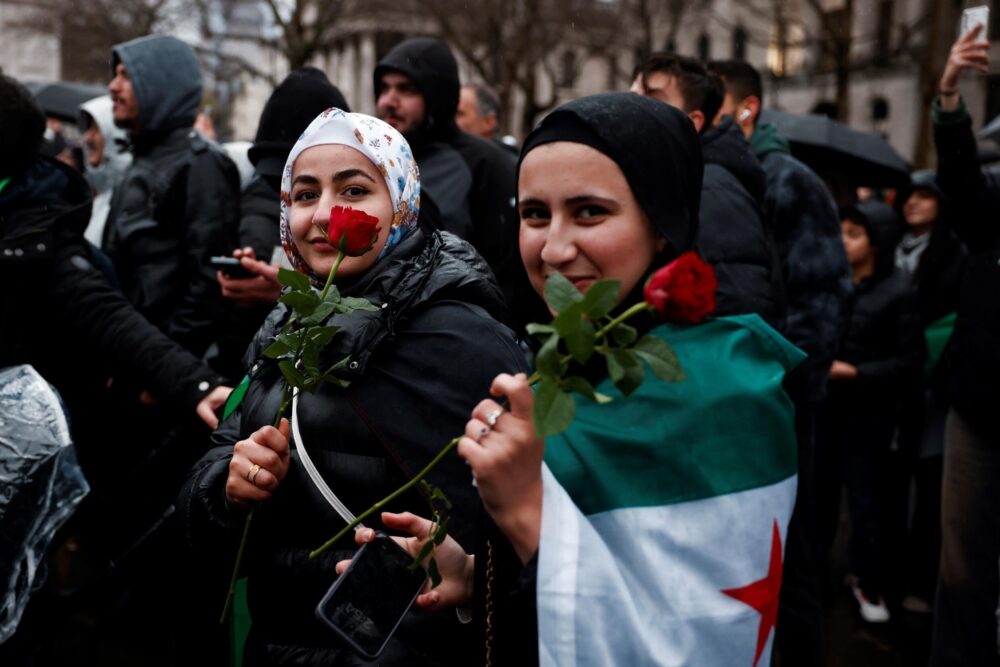 Dos manifestantes con sendas rosas en la mano asisten a una concentración de la comunidad siria en Londres para celebrar la caída del régimen de Bashar al Asad, el 8 de diciembre de 2024 en Trafalgar Square, en Londres