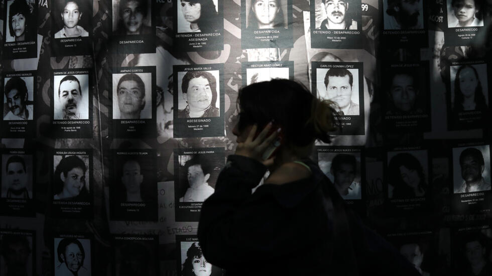 Una mujer camina frente a una pancarta con fotografías de personas desaparecidas en el Día Internacional de Víctimas de Desaparición Forzada en Medellín, Colombia, el 30 de agosto de 2024.