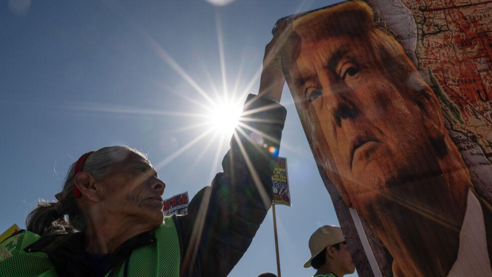 Una manifestante sostiene una pancarta con la imagen del presidente electo de EEUU, Donald Trump, durante una protesta en el paso fronterizo de San Ysidro, en Tijuana, México, el 18 de diciembre de 2024, Día Internacional del Migrante